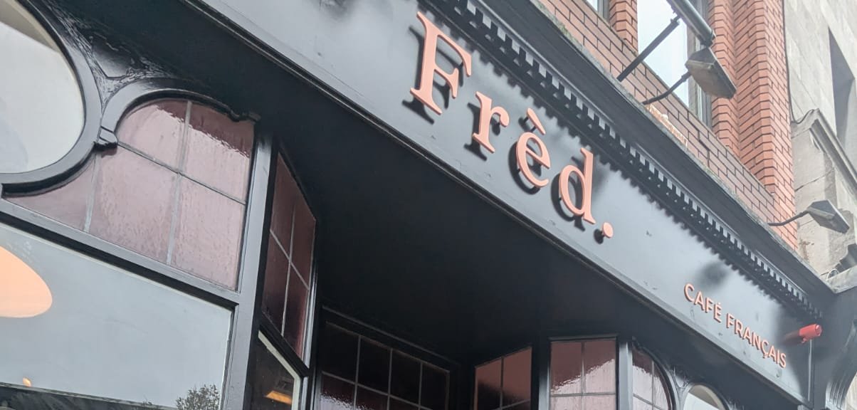 The Frèd. shopfront on Nassau Street: black fascia with the coral 'Frèd.' wordmark and 'Café Français' beneath it.